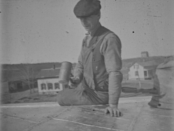 Roofer flattens metal roofing with mallet in De Kalb