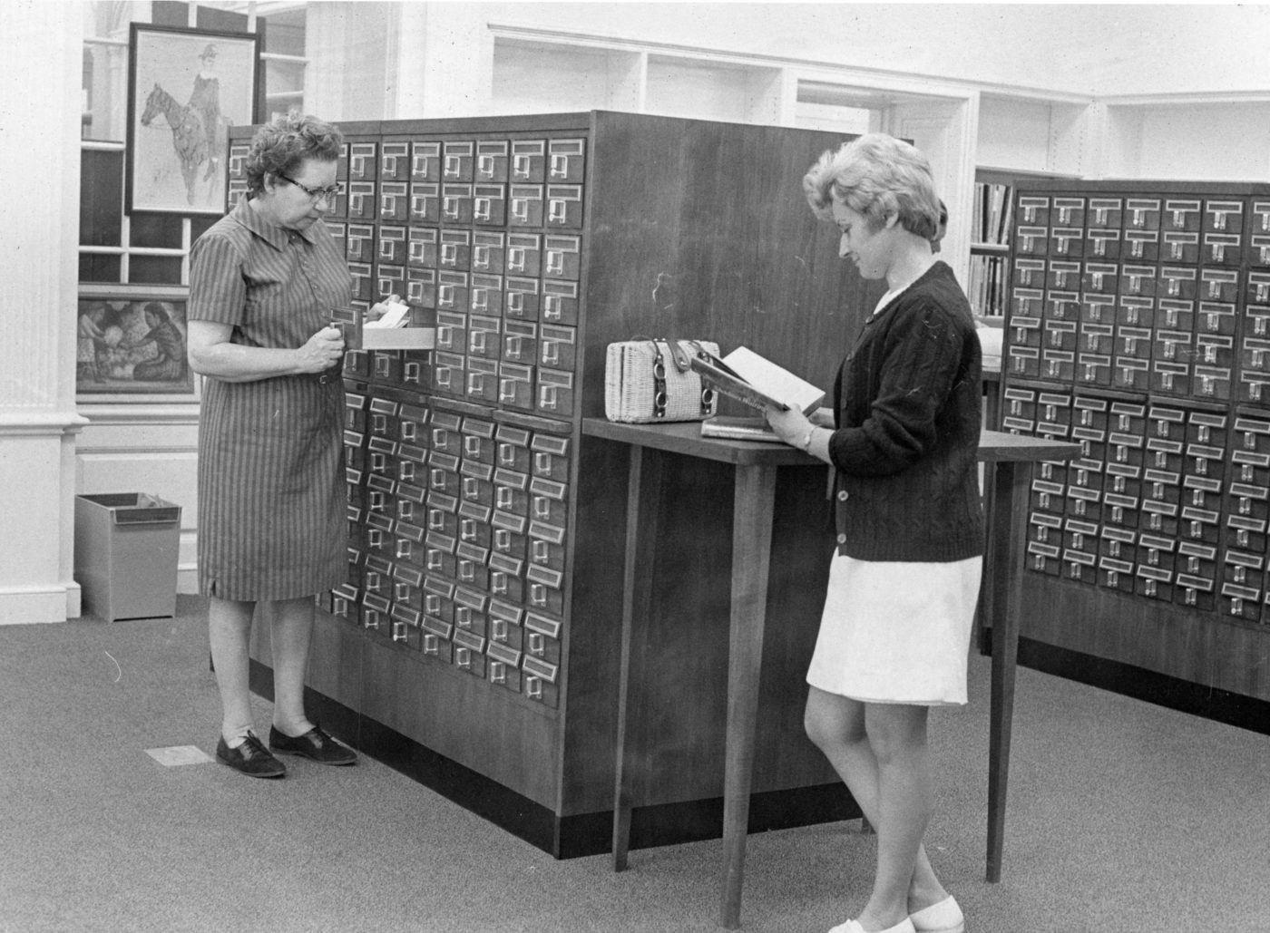 Reference Librarian and patron look through the card catalog at