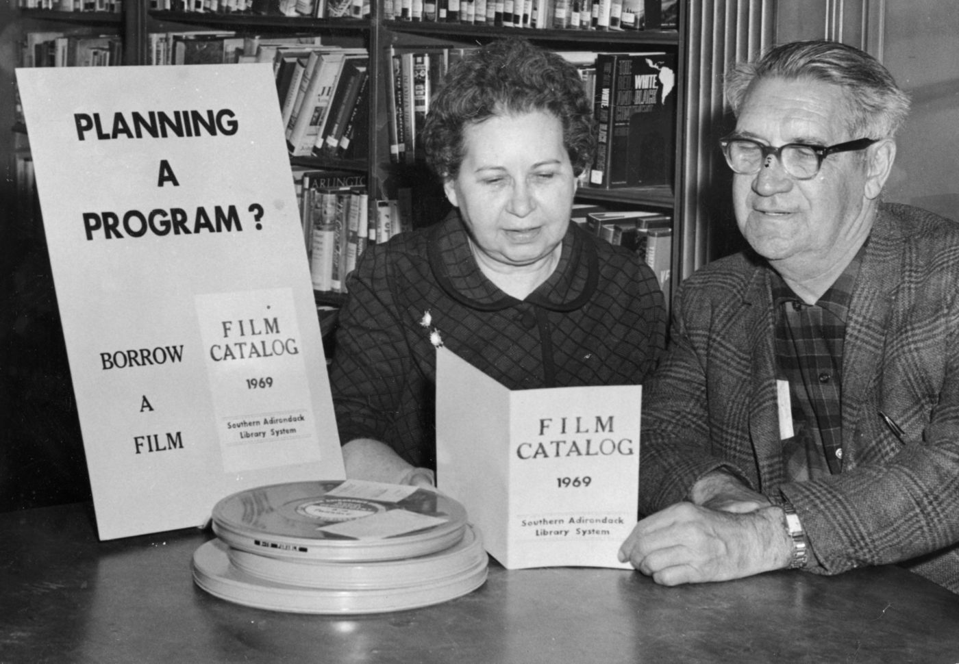 Librarian McAndrews shows film catalog to a patron at the Crandall